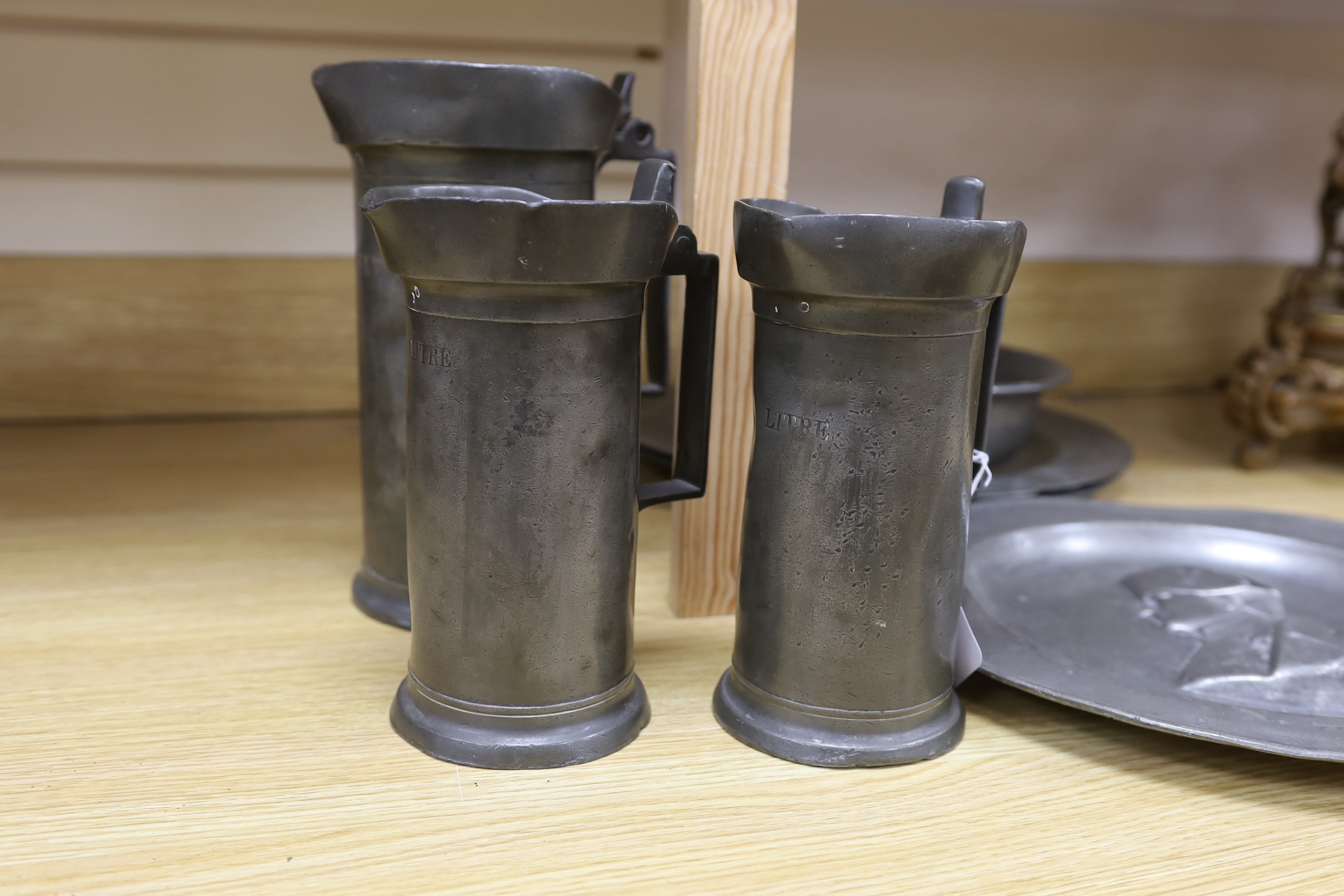 Three 18th century French pewter flagons and chargers, largest 39cm diameter